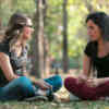 Zwei Frauen im Gespräch, auf Waldboden sitzend
